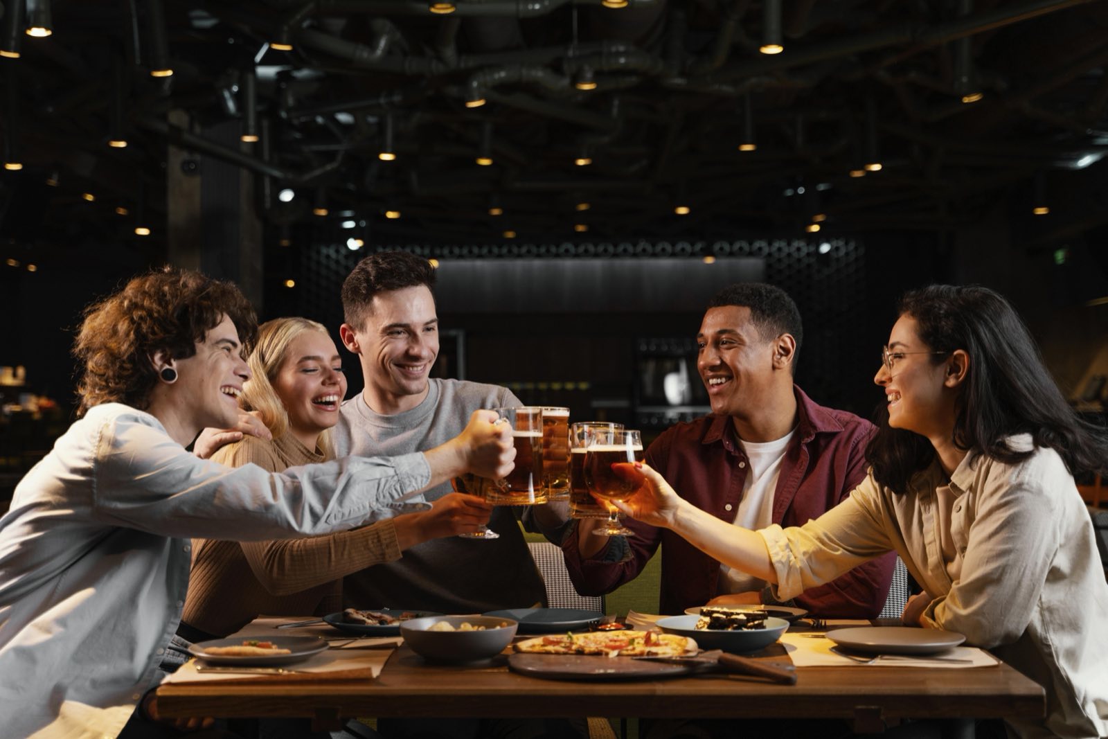 Grupo a brindar com cerveja numa mesa de bar